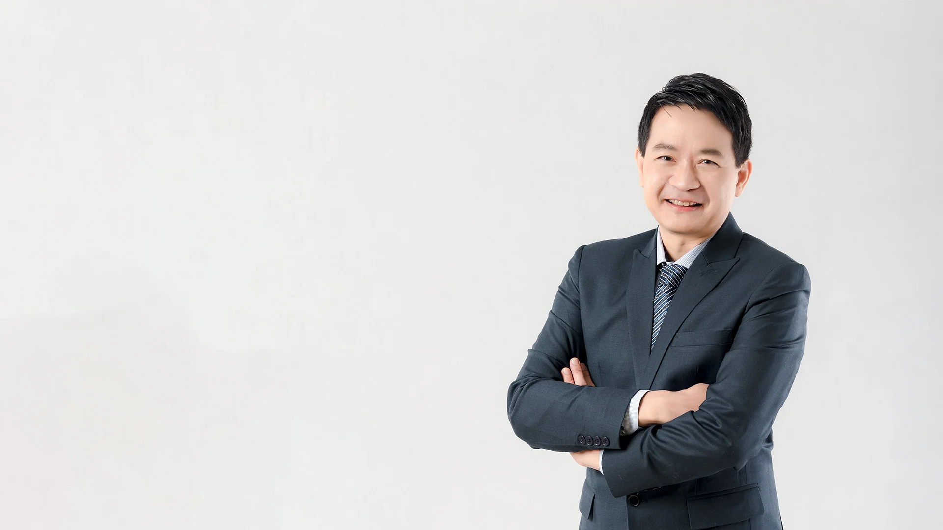 Dr. Chettawut Tulayaphanich standing confidently with arms crossed.