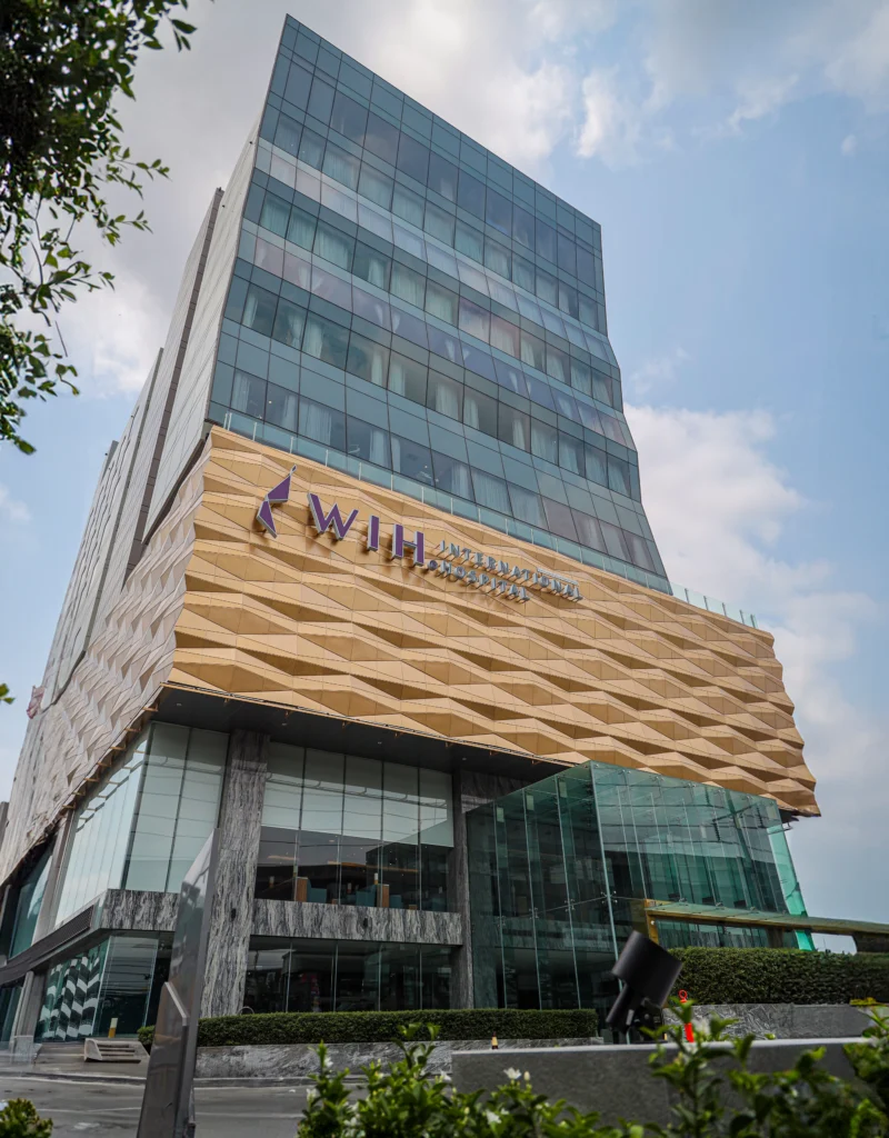 Modern building with glass facade and wooden signage, representing WIH International Hospital.